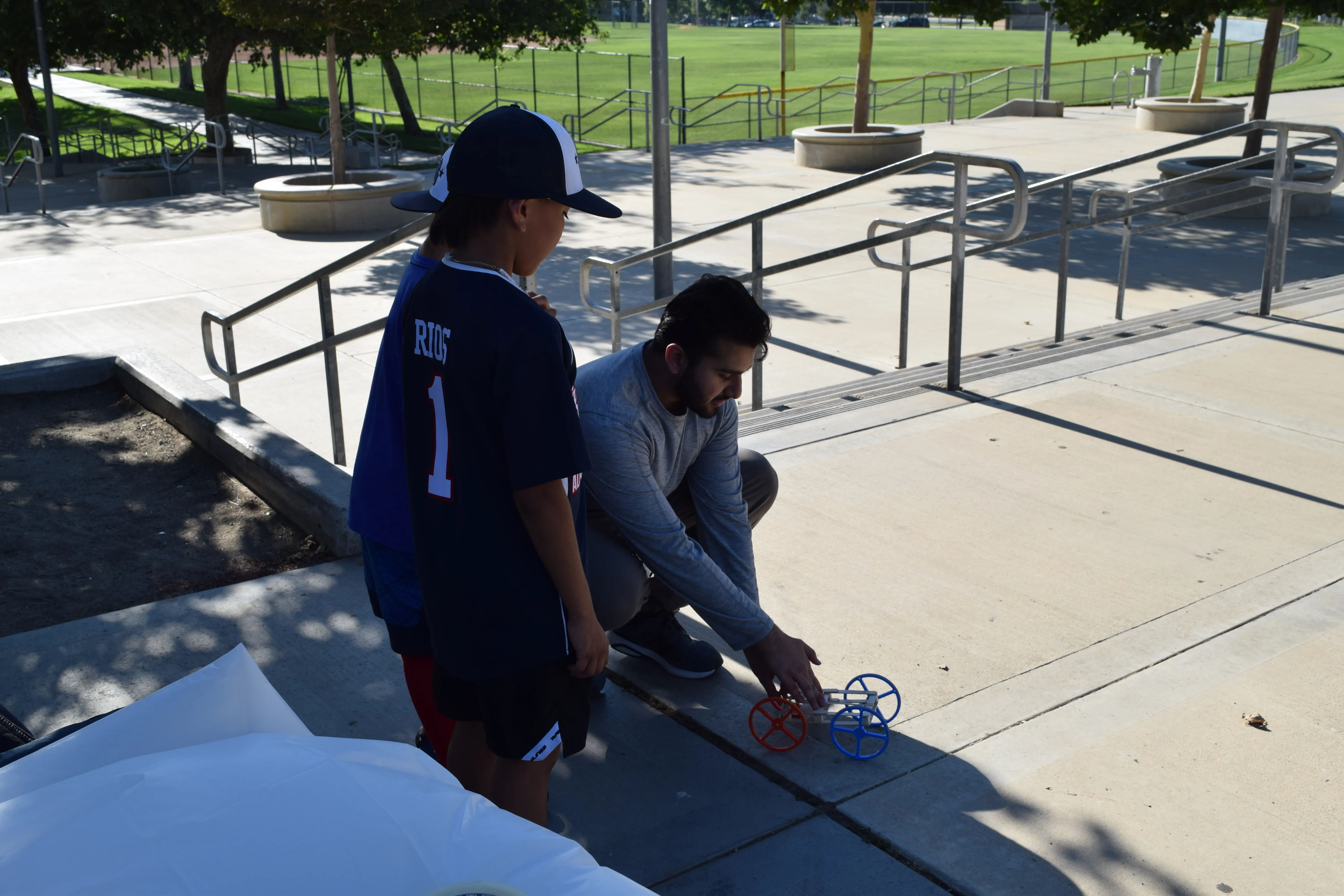 A STEM Inspire mentor works with a student on a rubber band car at Orange Terrace Park.