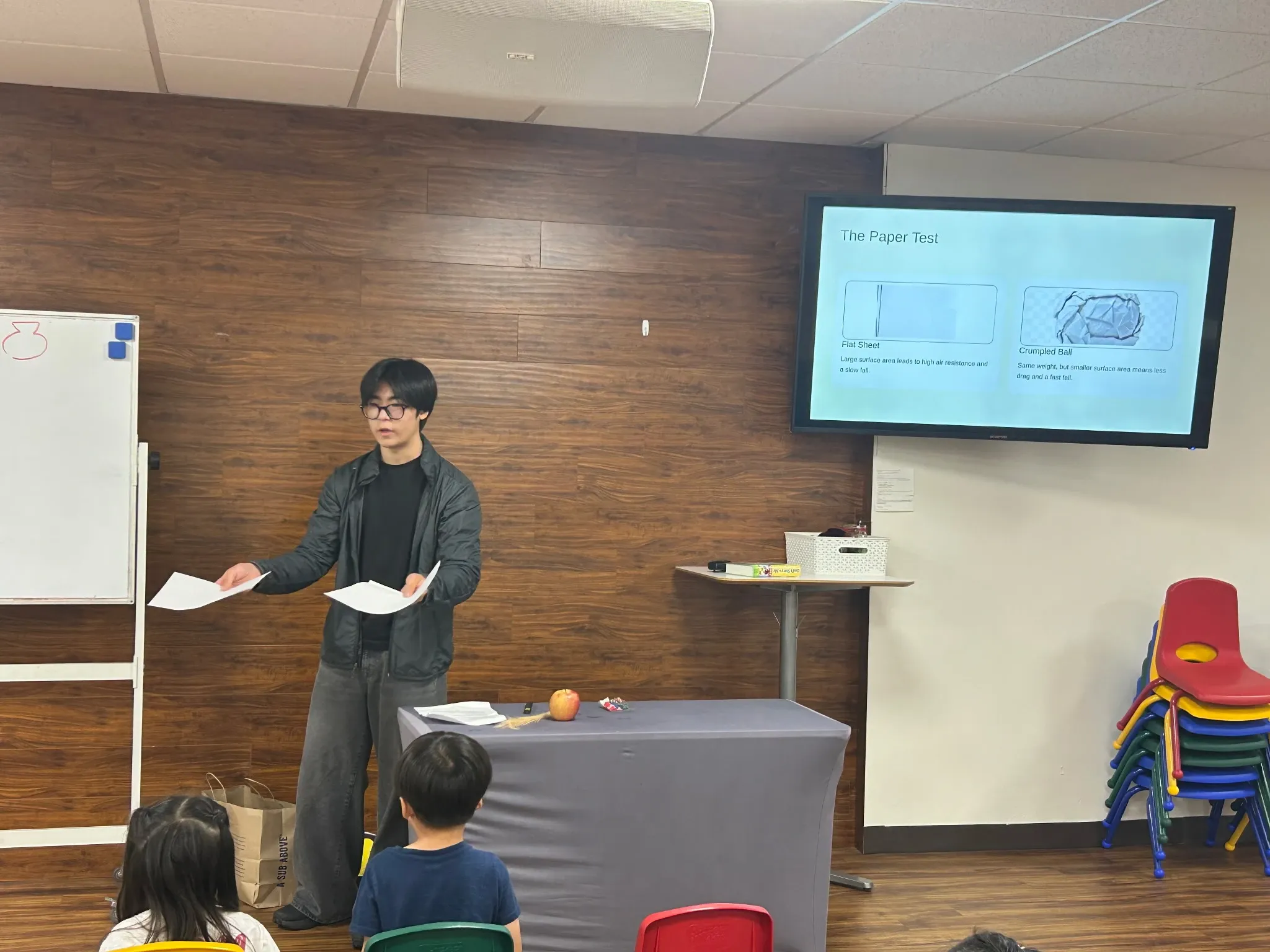 Jack Lee holds a flat sheet of paper and a second sheet during the paper test on air resistance.