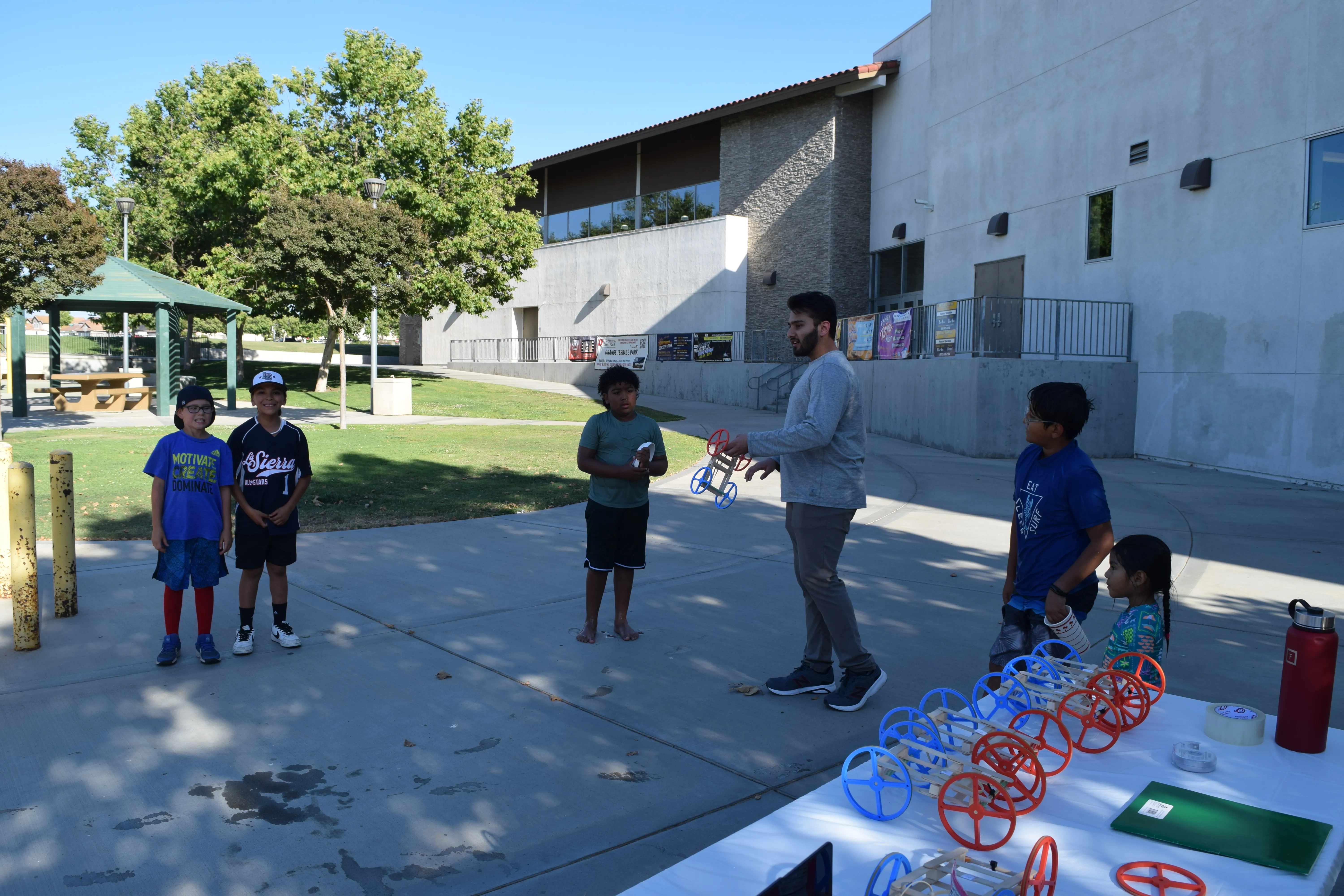 Students gather around rubber band cars during the Riverside STEM Inspire event.