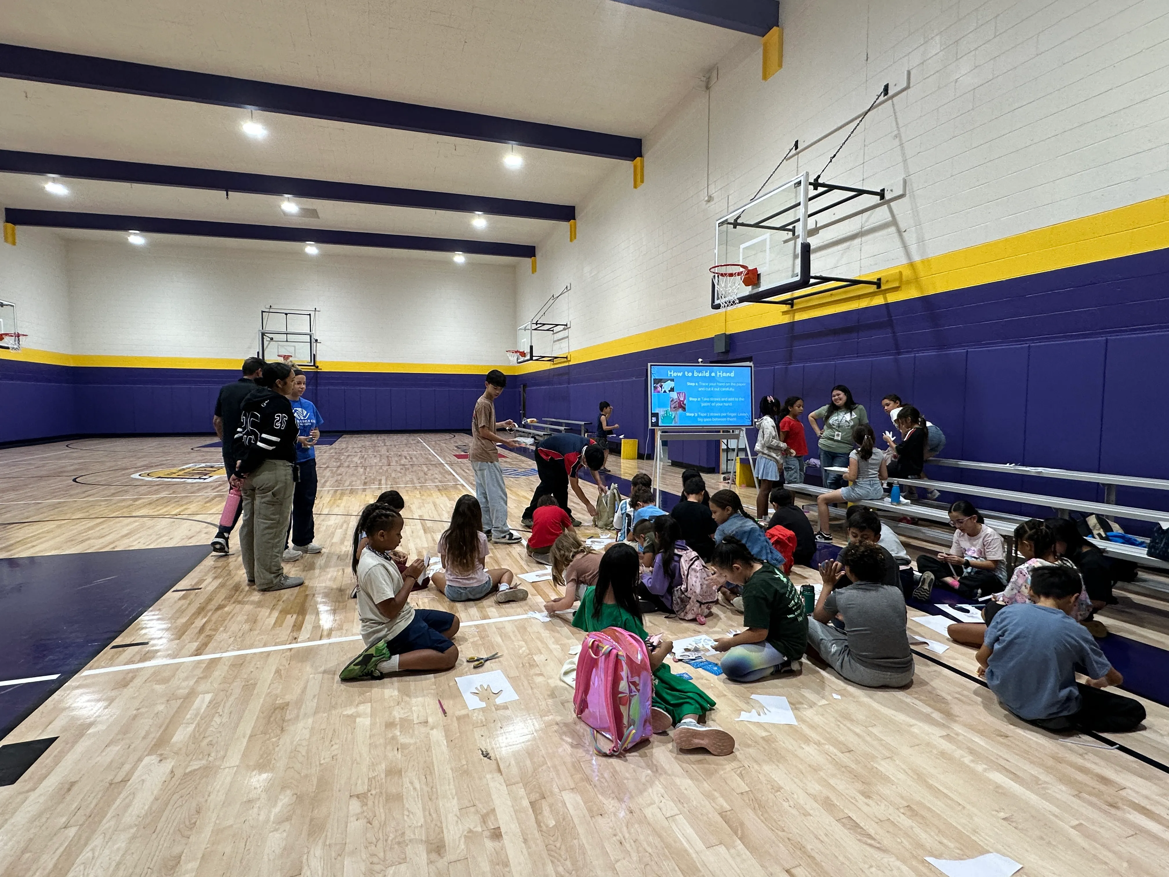 Students gather for a paper-hand activity in the Boys and Girls Club gym.